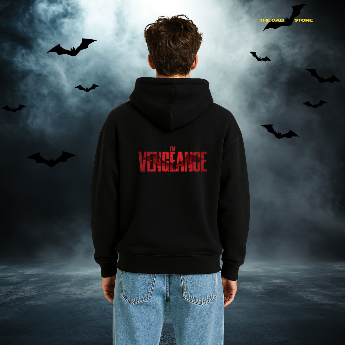 A person facing away, wearing a black hoodie with "I'm Vengeance" in red on the back. Bats fly overhead against a cloudy, dark sky, creating a moody atmosphere.